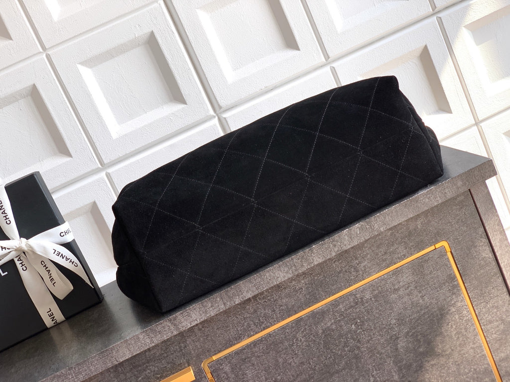 Black quilted bag on a gray surface with a white tiled wall in the background