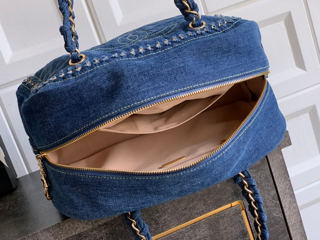 Blue denim handbag with gold accents on a wooden surface