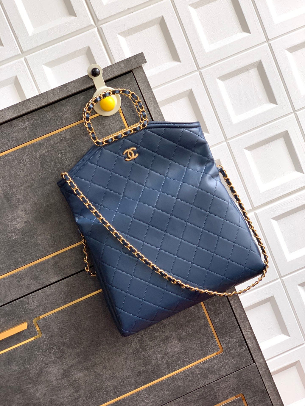 Blue quilted handbag with gold chain and CC logo on a textured surface