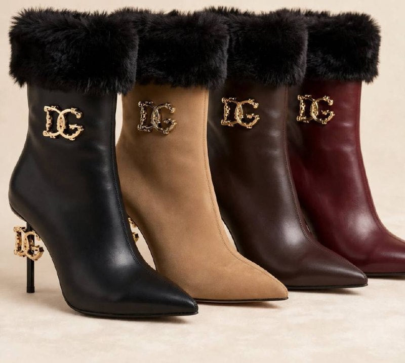 Four pointed-toe ankle boots with black faux-fur trim and gold-tone 'DG' logo hardware, shown in black, tan, brown, and burgundy on a light beige background.