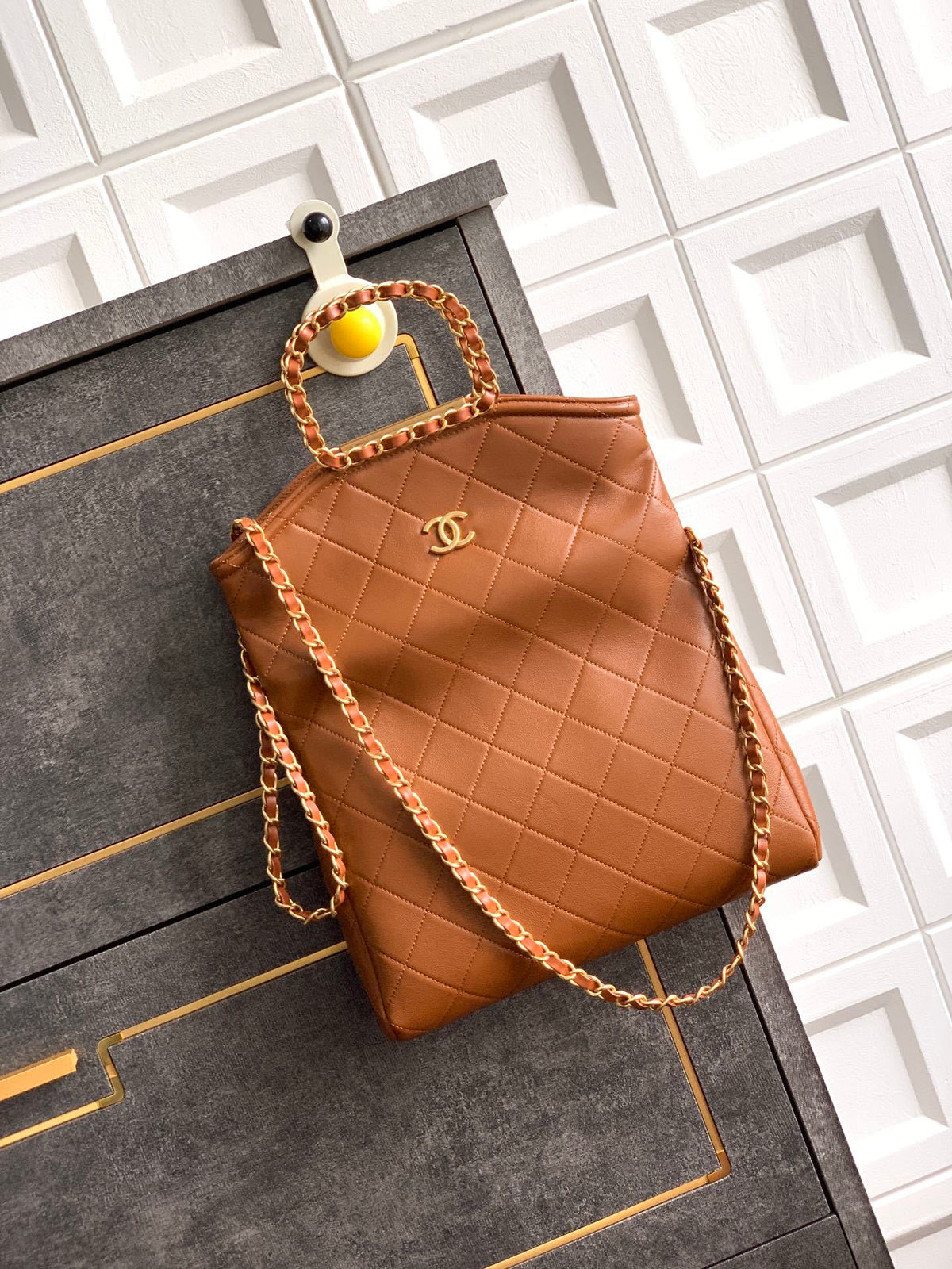 Brown quilted handbag with chain detail on a textured surface