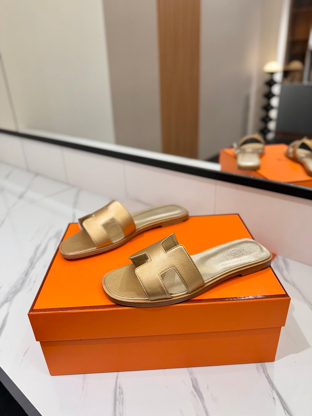 Gold sandals on an orange box with a blurred background