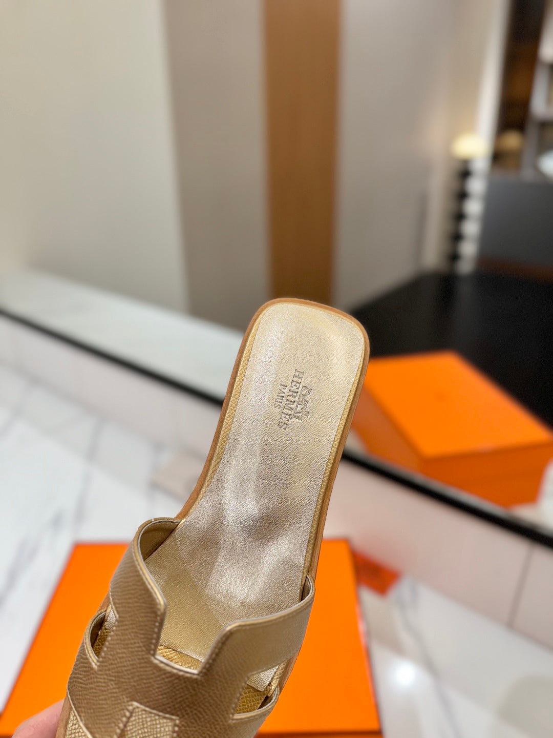 Beige sandal with brand logo on a blurred background