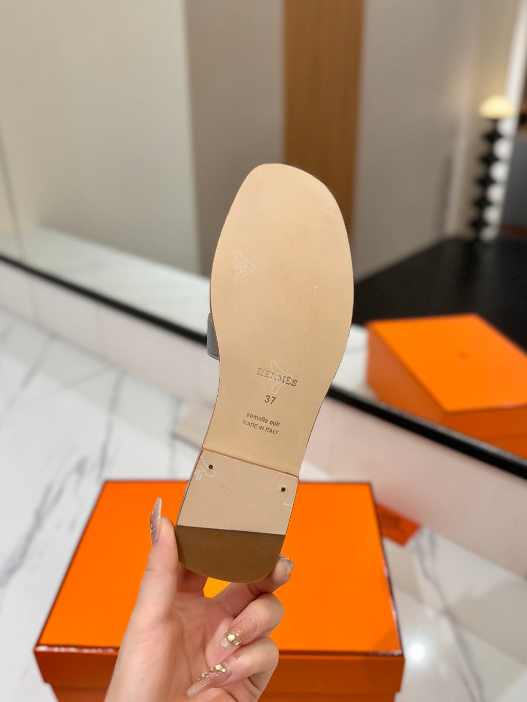 Beige shoe insole held by a hand with an orange box in the background