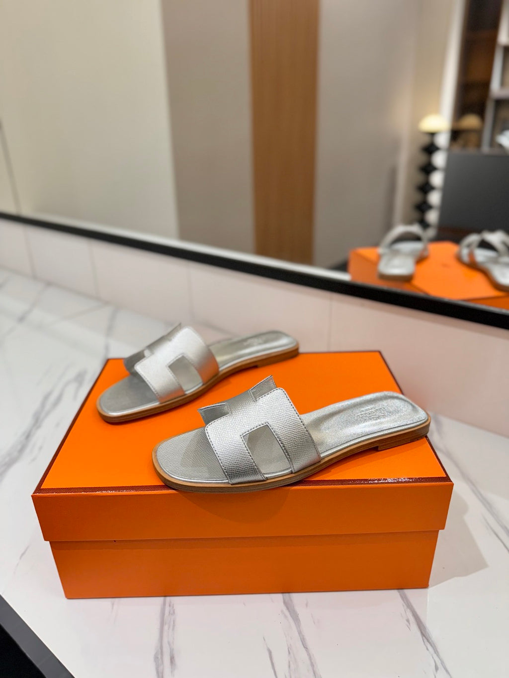 Silver sandals on an orange box with a blurred background