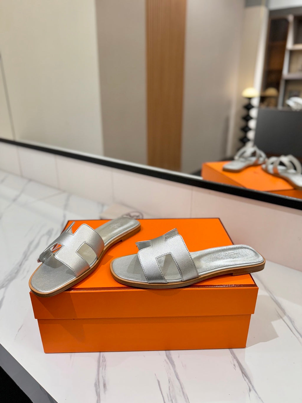 Silver sandals on an orange box with a blurred indoor background
