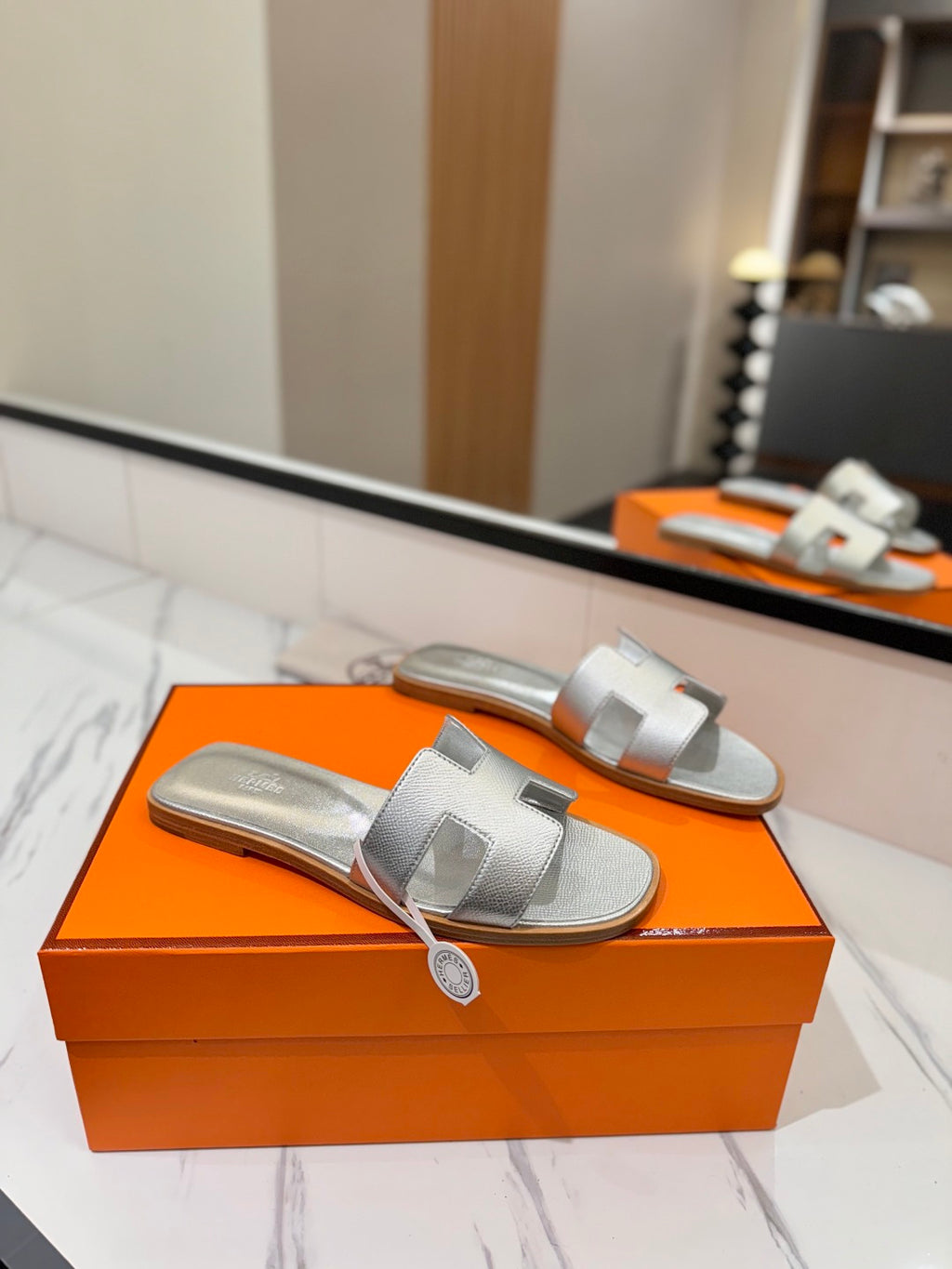 Silver sandals on an orange box with a blurred indoor background