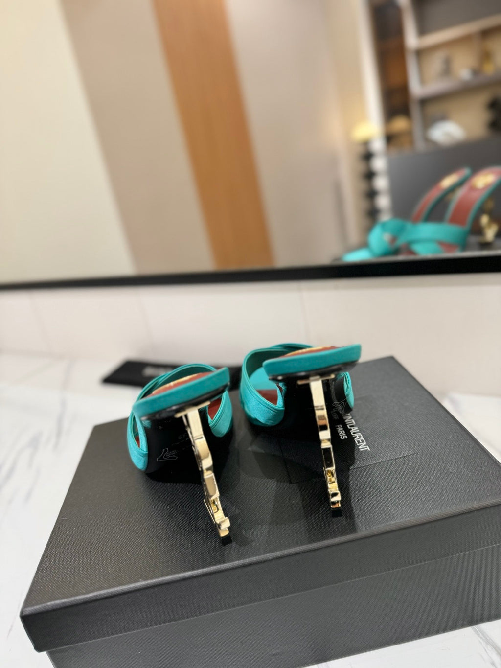 A pair of Gucci men's leather loafers in turquoise blue with gold-tone hardware and a thin red stripe, displayed on top of a black Gucci box.