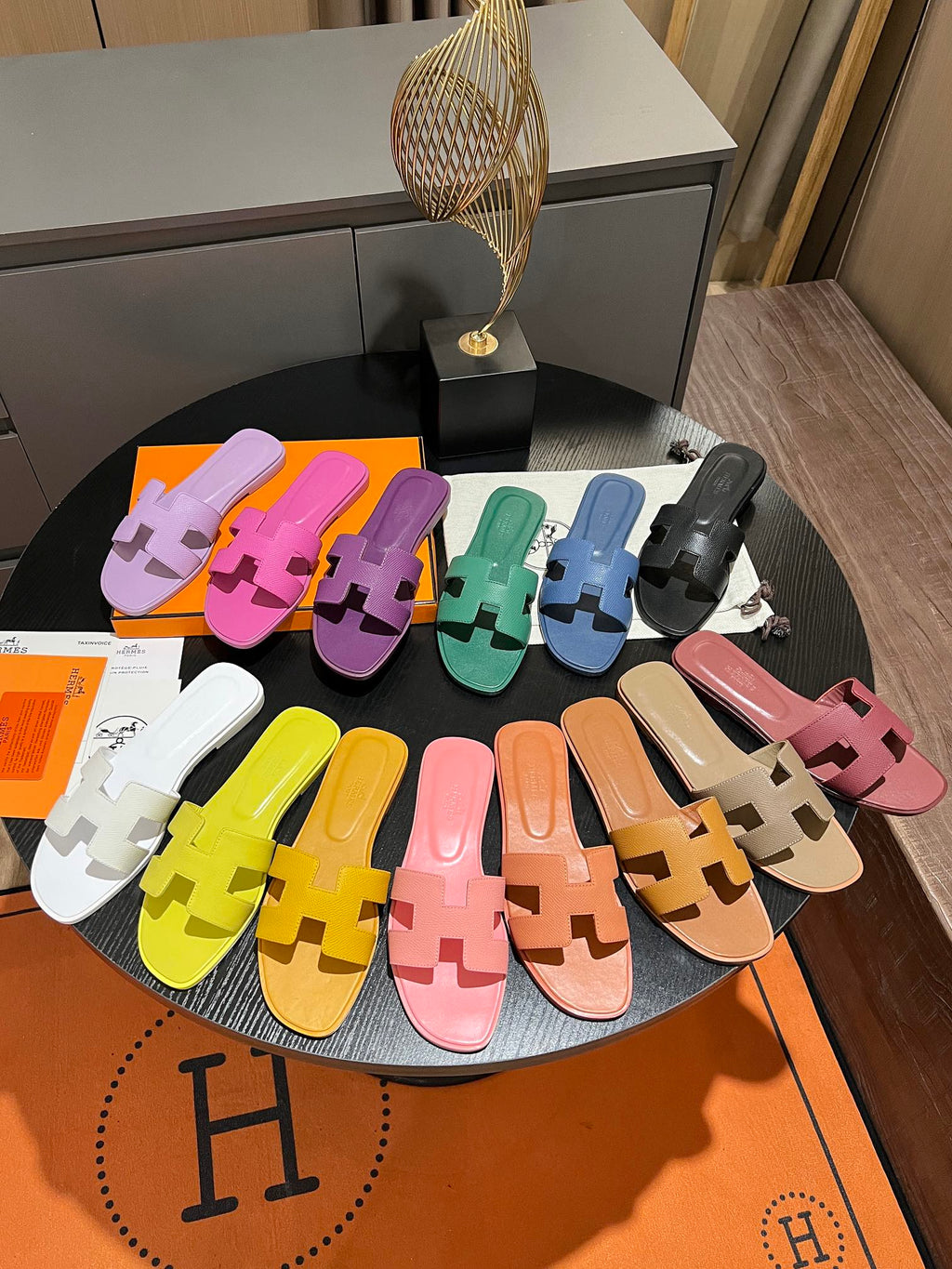 Colorful slippers arranged on a round table with a visible brand logo.